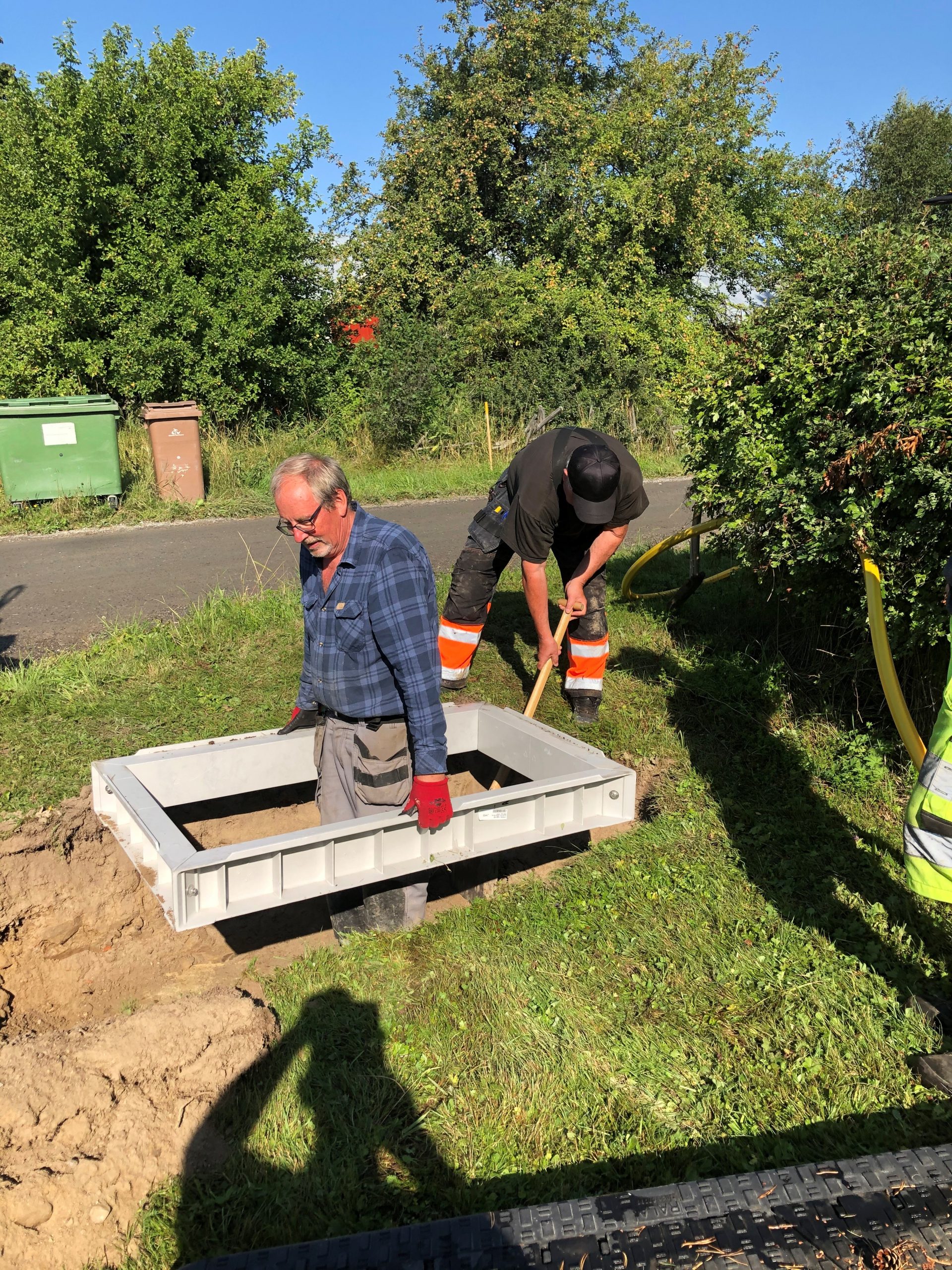 Två människor gräver och jobbar i trädgården. 