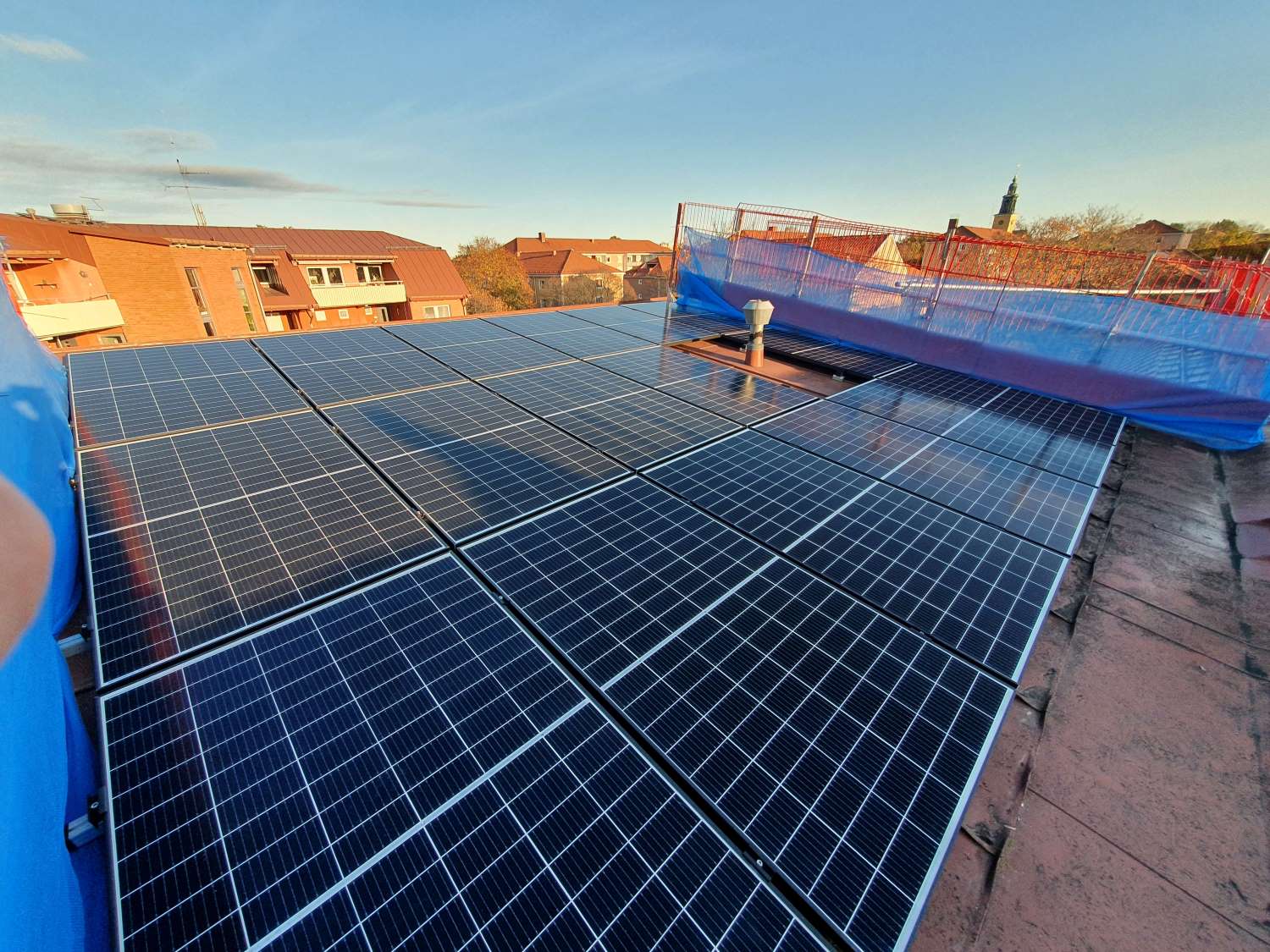 Vy över solceller på taket av ett lägenhetshus.
